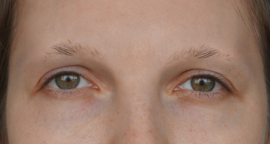 Close-up of a person's face highlighting their eyes, which feature light brown irises and minimal makeup. The focus on the eyes suggests emotions or expressions.