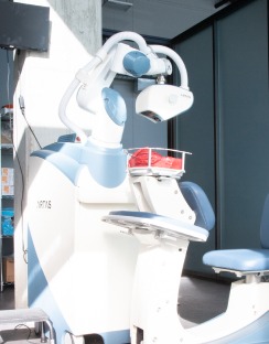 Dental robotic assistant positioned next to a treatment chair, featuring advanced imaging equipment for enhanced dental procedures.