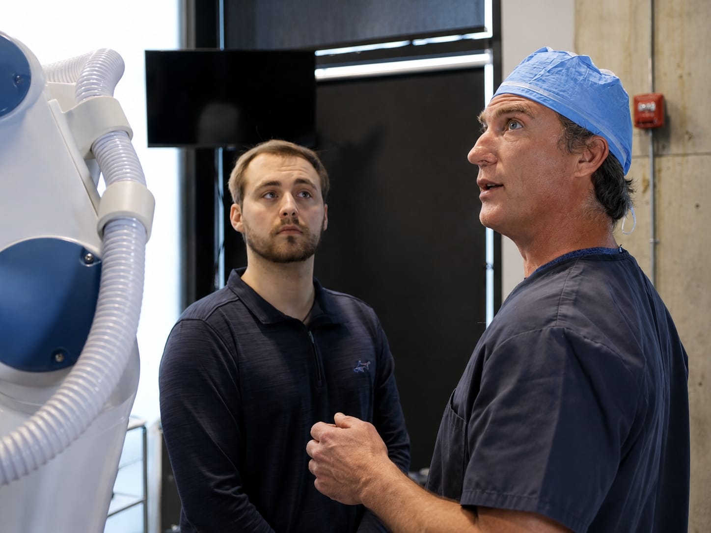 Surgeon explaining robotic and manual hair transplant options beside the ARTAS system